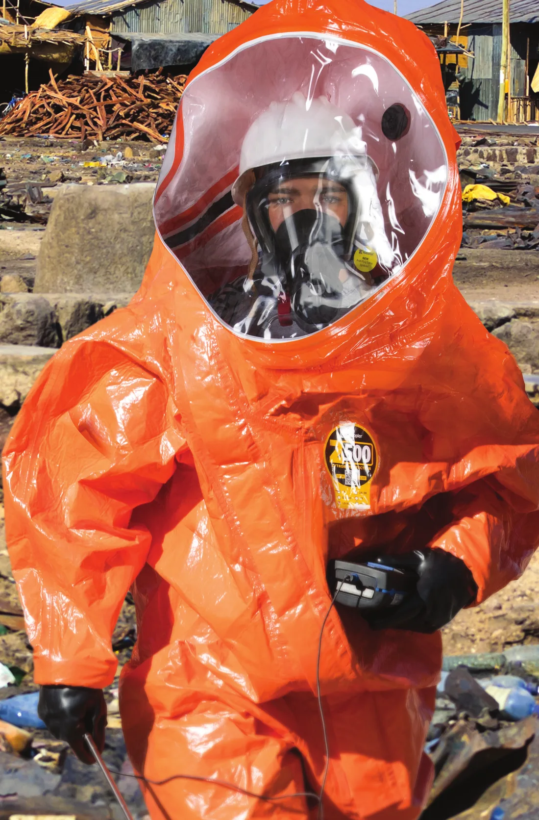 Responder in an orange Kappler Zytron 500 gas-tight total encapsulating suit with SCBA, holding a meter